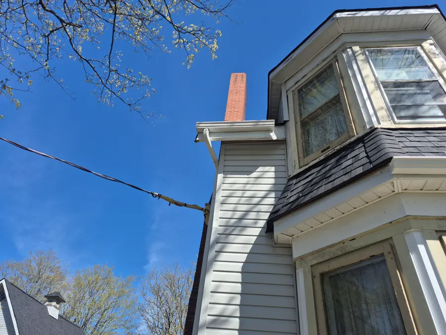 The witch-hat turret after: sleek black cone over new grey siding