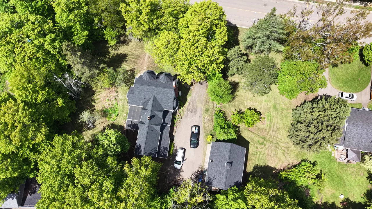 The finished the Sackville Victorian property from the air: new black roof, new siding, carriage house and grounds