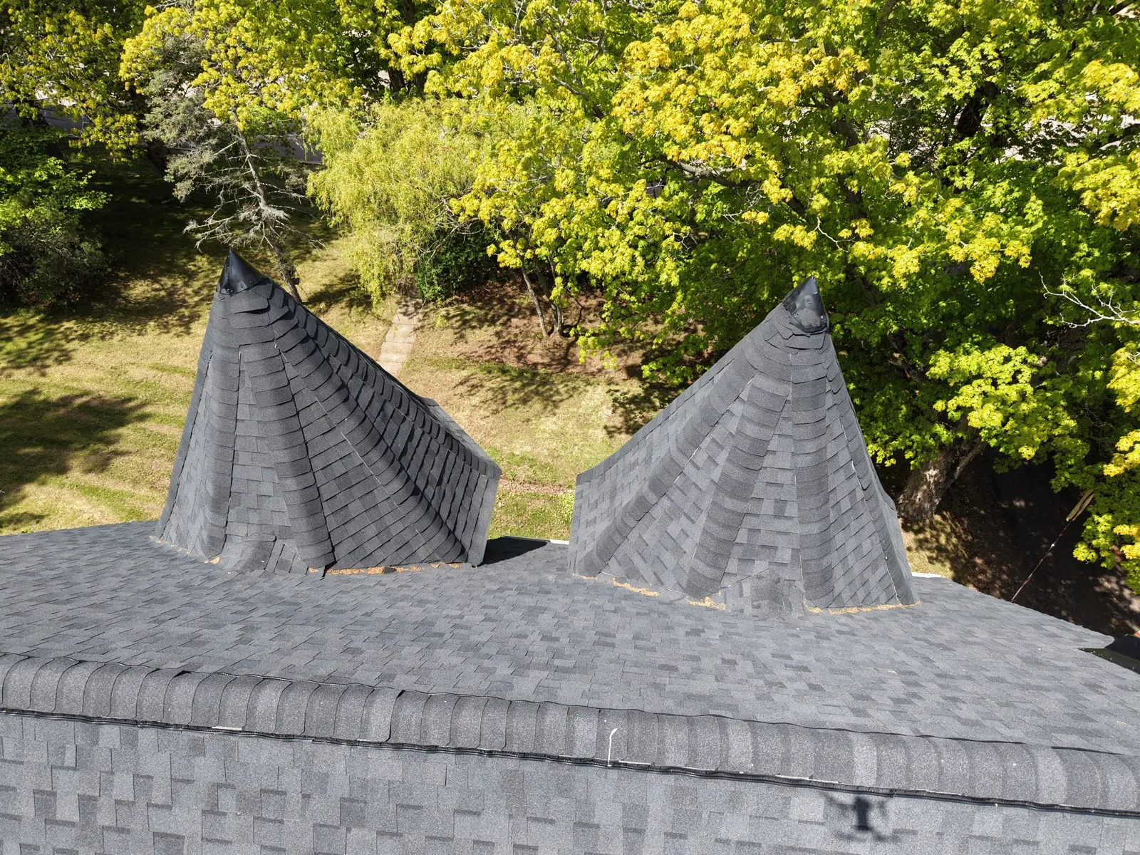 Twin witch-hat turret cones with new black shingles on the restored Sackville Victorian, drone detail